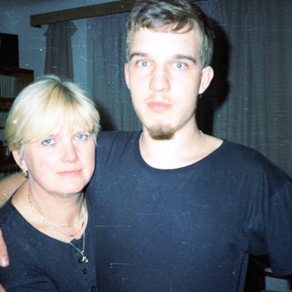 Two people posing indoors, smiling slightly.