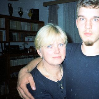 Two people posing indoors, smiling slightly.