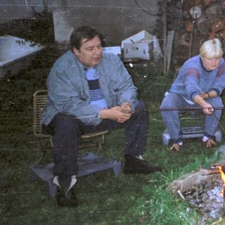 Three people cooking over an outdoor fire.