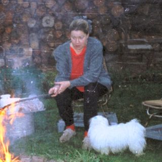 Three people cooking over an outdoor fire.