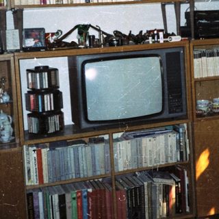 Vintage wooden bookshelf with books, old CRT TV, and miscellaneous items.