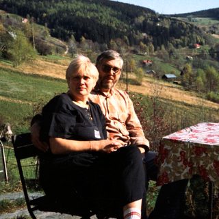 Two people sitting outdoors in rural countryside setting.