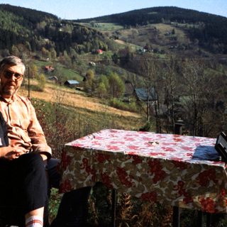 Two people sitting outdoors in rural countryside setting.
