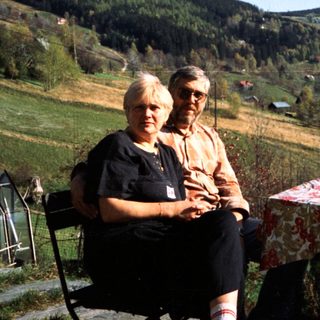 Two people sitting outdoors in rural countryside setting.