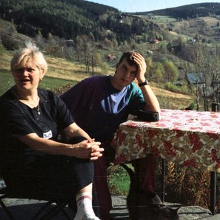 Two people sitting outdoors by a scenic table.