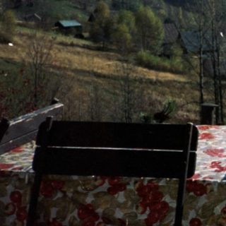 Rural valley scene with rolling hills, forest, and picnic table.