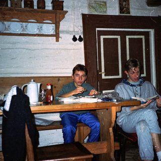 Two individuals studying indoors at wooden table.