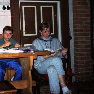 Two individuals studying indoors at wooden table.