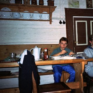 Two individuals studying indoors at wooden table.