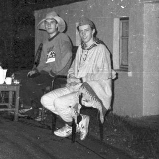 Two men posing outside a building at night.