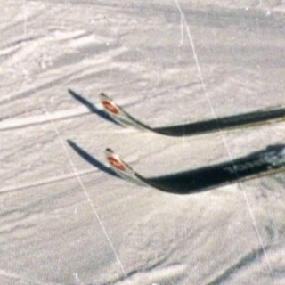 Skiers descending snowy mountain under clear sky.