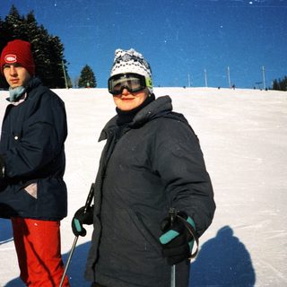Two people cross-country skiing on snow-covered trail.