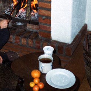 Cozy room with man sitting by lit fireplace.