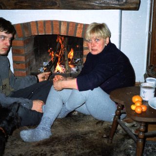 Cozy indoor scene with two people by fireplace.