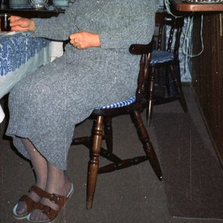 Woman sitting in cozy kitchen with vintage decor.