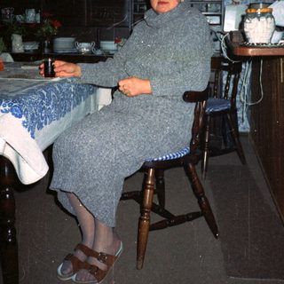 Woman sitting in cozy kitchen with vintage decor.