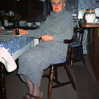 Woman sitting in cozy kitchen with vintage decor.