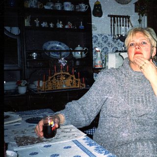 Woman sitting at table with candle, indoors.