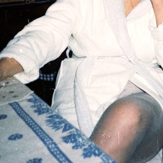 Woman in white robe posing in vintage kitchen.