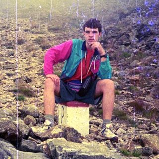 Person hiking in misty mountainous terrain.
