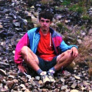 Person sitting on rocky stream bed.