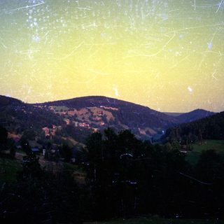 Night sky with meteor shower over mountainous landscape.