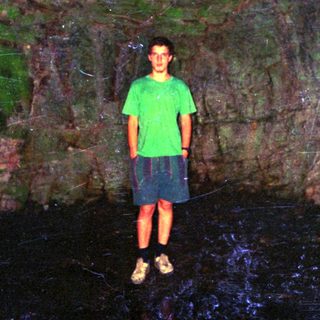 Person standing in dark cave entrance.