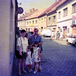 Family posing on cobblestone street in vintage European town.