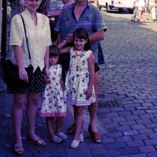 Family posing on cobblestone street in vintage European town.