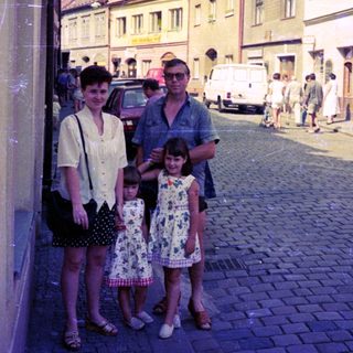 Family posing on cobblestone street in vintage European town.