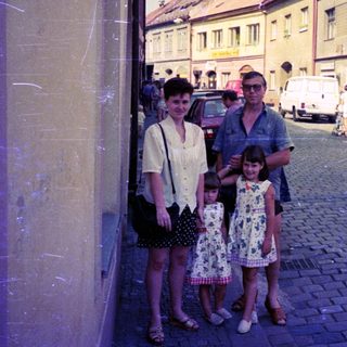 Family posing on cobblestone street in vintage European town.