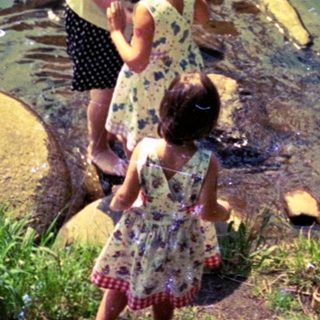 Family enjoying shallow river water near rocks.