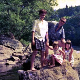 Family fishing by river at sunset.