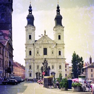 Baroque church with twin towers on wet cobblestone square.