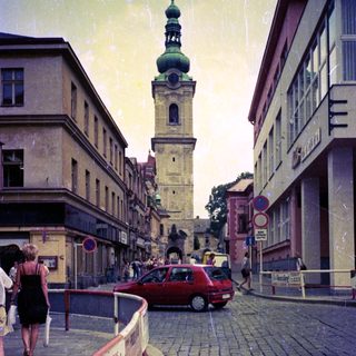 European street scene with historic tower and cobblestone road.