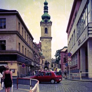 European street scene with historic tower and cobblestone road.