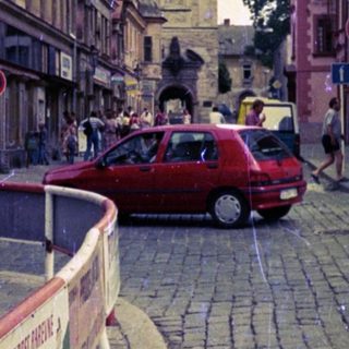 European street scene with historic tower and cobblestone road.
