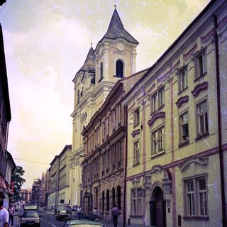Historic European street with classic architecture and vintage cars.