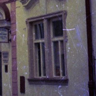 Historic European street with classic architecture and vintage cars.