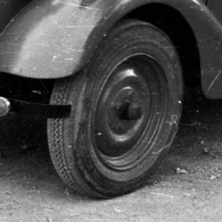 Vintage military-style open-top car with license plate.