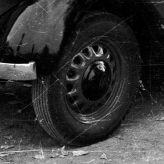 Vintage car damaged near tennis court.