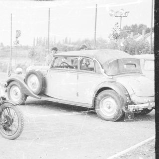 Vintage car and motorcycle parked outdoors.
