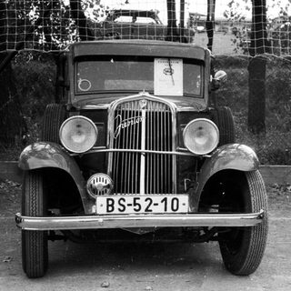 Vintage car BS-52-10 with woman standing nearby.
