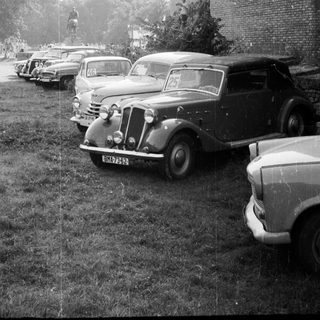 Vintage cars parked near historic brick wall.