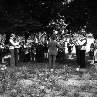Funeral procession with brass band playing at gravesite.