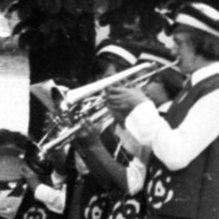 Funeral procession with brass band playing graveside.