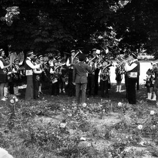 Group playing brass instruments at outdoor gravesite ceremony.