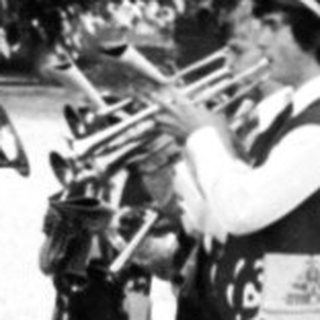 Group playing brass instruments at outdoor gravesite ceremony.