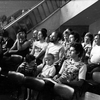 Group of people watching event indoors.