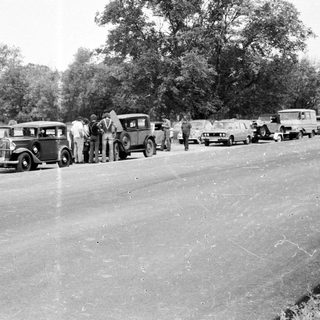 Vintage cars lined up on a rural road.
